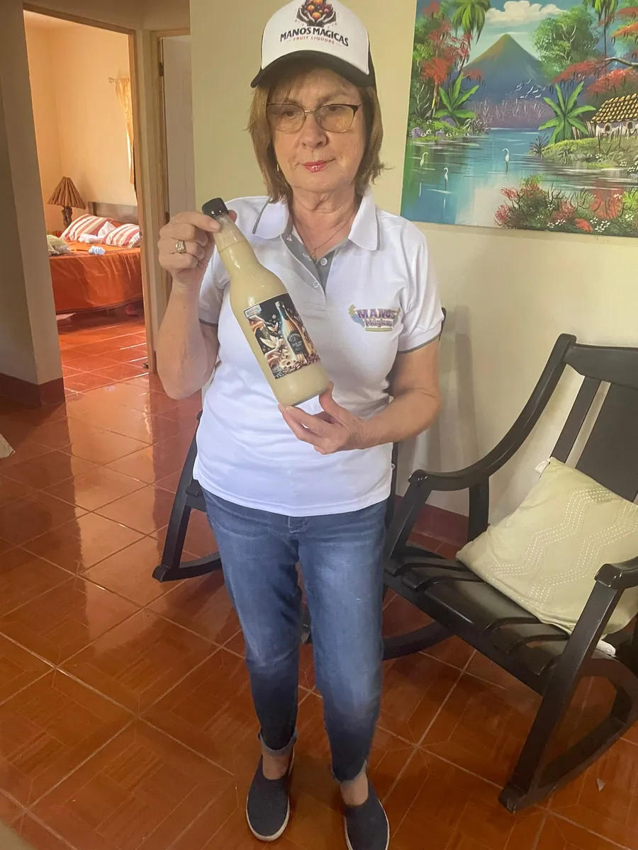 Fundadora de Manos Mágicas sosteniendo una botella de licor artesanal